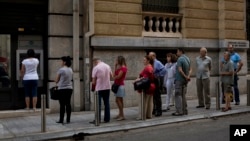 People line up to withdraw cash from a bank machine in central Athens, July 7, 2015. 
