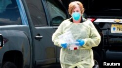 Una trabajadora de salud inicia el proceso para usar una nueva prueba de detección de la COVID-19 basada en la saliva, en un punto de pruebas en Edison, Nueva Jersey, el 15 de abril de 2020. 