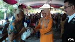 Ibunda Presiden Joko Widodo, Sujiatmi (tengah), menyerahkan paket sembako untuk warga di Solo. (VOA/Yudha Satriawan)