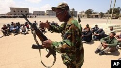 A rebel army officer teaches the use of a weapon to civilians, who have volunteered to join the rebel army, in Benghazi, May 11, 2011