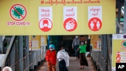 ရန်ကုန်မြို့ ပန်းဆိုးတန်းဆိပ်ခံတံတားမှာ ချိတ်ဆွဲထားတဲ့ ကိုဗစ် သတိပေးချက်ဆိုင်းဘုတ်နဲ့ နှာခေါင်းစည်းတပ် သွားလာနေကြသူများ။ (ဇူလိုင် ၂၇၊ ၂၀၂၁)