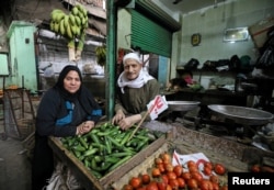Hayes Mehana (R), 78, and Om Hany, 60, pose for a photograph at a vegetable market in Cairo, Egypt, Feb. 12, 2018.