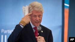 Former president Bill Clinton gestures while wearing a bracelet given to him by Kenyan students, as he and and his daughter Chelsea Clinton talk about their foundation's "No Ceilings" project at Farasi Lane Primary School in Nairobi, Kenya, May 1, 2015.