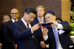 Harry Shum, right, Microsoft executive vice president of technology and research, demonstrates Micosoft's HoloLens device to Chinese President Xi Jinping, left, during a tour of Microsoft's main campus in Redmond, Washington, Sept. 23, 2015.