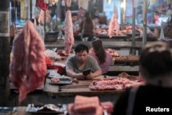 FILE - Vendors at their pork stalls at a market in Hekou Yao Autonomous County, Yunnan province, China, May 3, 2019.