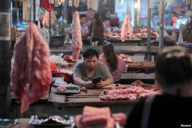 FILE - Vendors at their pork stalls at a market in Hekou Yao Autonomous County, Yunnan province, China, May 3, 2019.