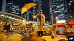 A protester holds an umbrella during a performance on a main road in the occupied areas outside government headquarters in Hong Kong, Oct. 9, 2014. 