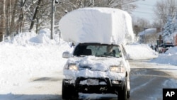 Chiếc xe chạy ra khỏi đống tuyết phủ, vẫn còn mang theo khối tuyết lớn trên mui xe sau trận tuyết rơi ở Lancaster, New York, 19/11/14