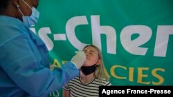 A health care worker performs a COVID-19 test on a traveller at OR Tambo International Airport in Johannesburg, Nov. 27, 2021, after several countries banned flights from South Africa following the emergence of the new COVID-19 variant Omicron.