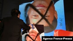 A demonstrator sprays paint over an upside-down portrait of Chinese leader Xi Jinping during an anti-China rally outside the parliament in Taipei on Oct. 1, 2021.