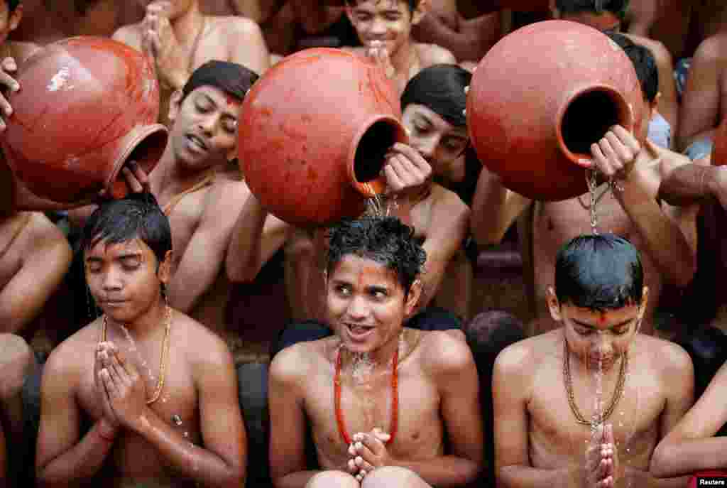 Students react as water from earthen pitchers is poured on them to take a holy bath during an annual month-long Hindu religious festival of Magh Mela in Ahmedabad, India.