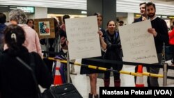 Des avocats accueillent les touristes et les résidents à l'aéroport international de Washington DC, le 31 janvier 2017. (VOA/Nastasia Peteuil)