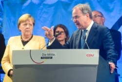 FILE - Christian Democratic Union (CDU) leader and top candidate for chancellor Armin Laschet speaks next to German Chancellor Angela Merkel during his election rally in Stralsund, Germany, Sept. 21, 2021.