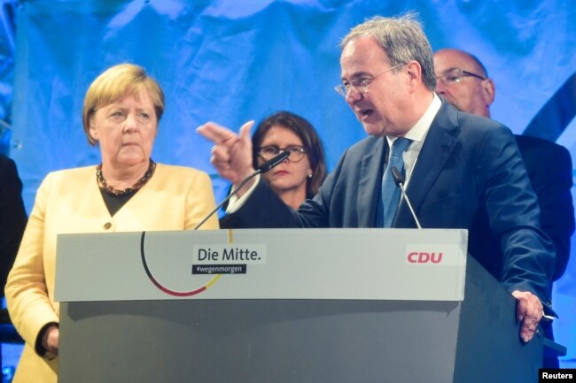 Christian Democratic Union (CDU) leader and top candidate for chancellor Armin Laschet speaks next to German Chancellor Angela Merkel during his election rally in Stralsund, Germany, Sept. 21, 2021.
