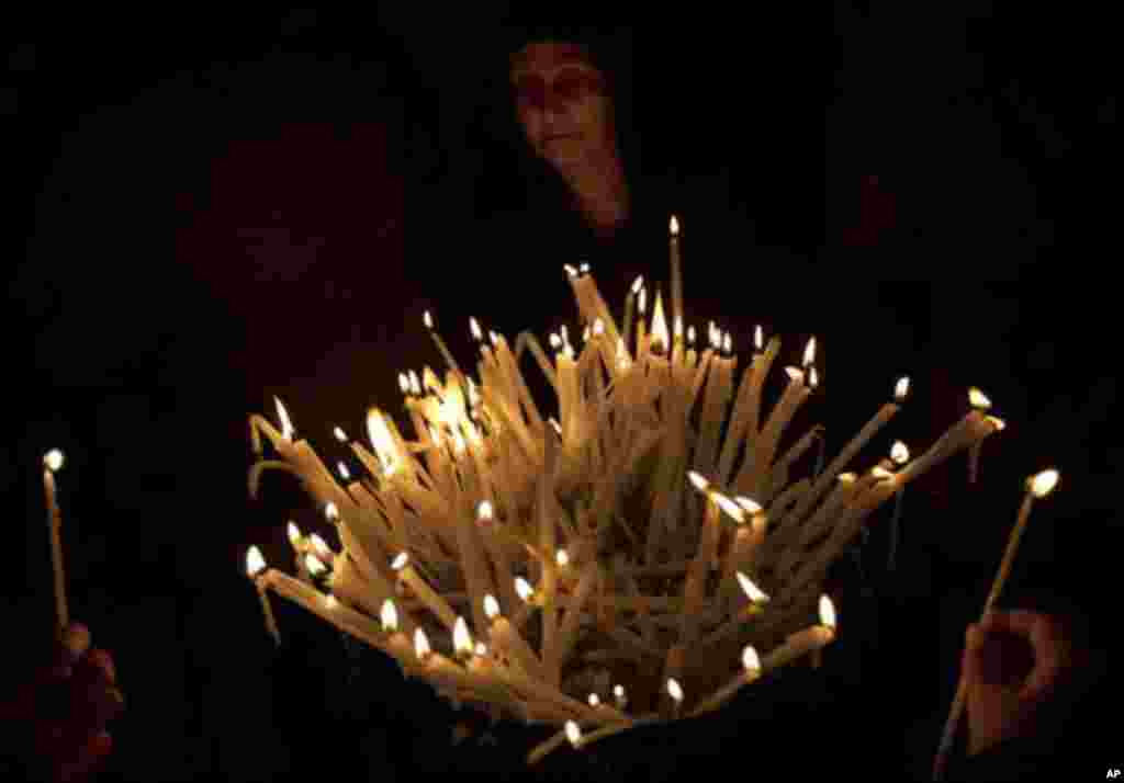 A Christian worshipper lights candles inside the Church of the Holy Sepulchre, traditionally believed to be the burial site of Jesus Christ, in Jerusalem's Old City, Sunday, April 8, 2012. (AP Photo/Sebastian Scheiner)