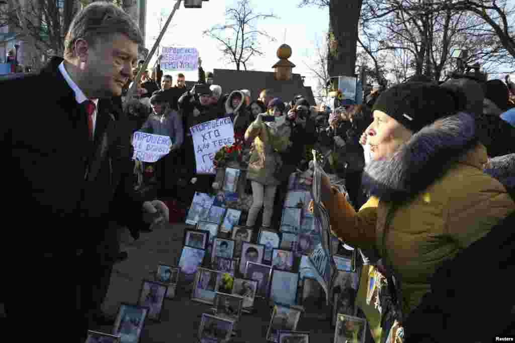 Ukrainian President Petro Poroshenko talks with a woman during a wreath laying ceremony at the monument to the fallen heroes of the &quot;Heavenly Sotnya&quot; (Hundred) in Kyiv, Nov. 21, 2014.