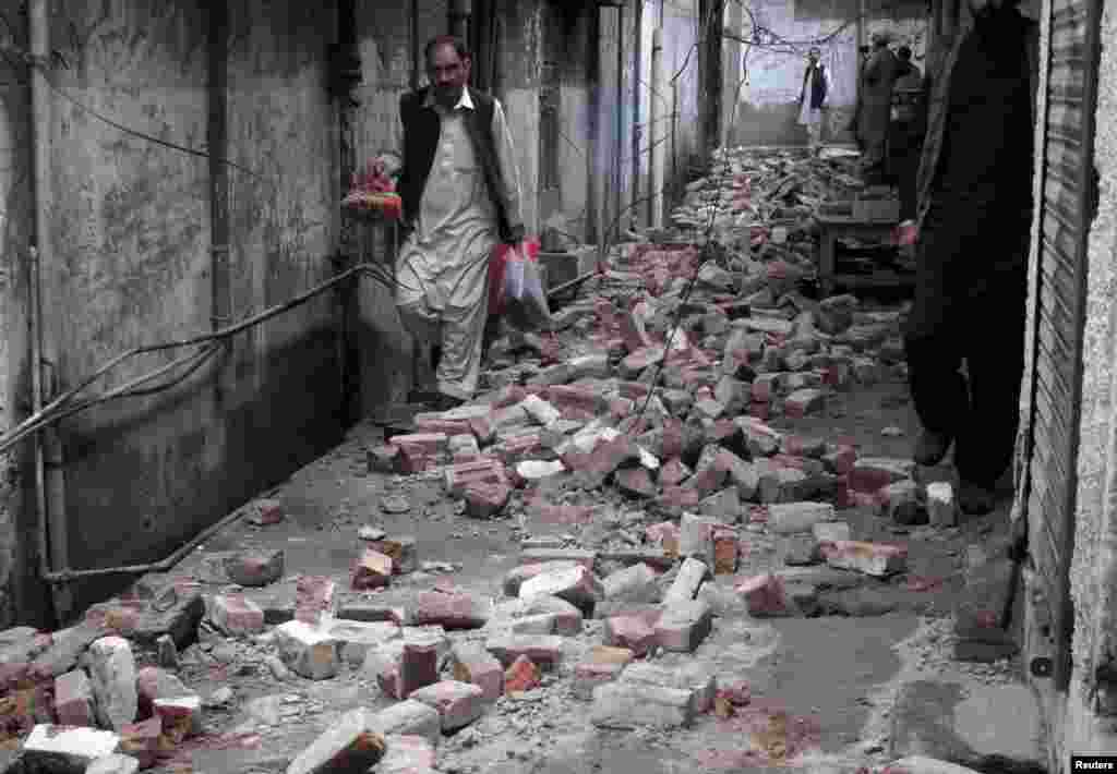 A man walks with his belongings past the rubble of a house after it was damaged by an earthquake in Mingora, Swat, Pakistan, Oct. 26, 2015.