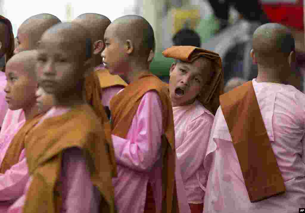 Waumini wachanga wa dini ya Budhaa wakiwa wamejipanga baada ya kutembea mitaani wakichukua zawadi katikati ya mji wa Yangon, Myanmar.