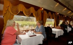 Julie Norris, left, of Florida, drinks a glass of wine while riding the Napa Valley Wine Train with Paula Anderson, of Connecticut, Oct. 19, 2017, in Oakville, California. The train resumed its runs this week after last week's wildfires.
