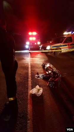 The body of a man killed in a collision lies covered on the side of a highway. (D.Taylor/VOA)