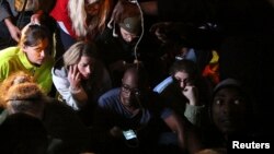 People listen to a radio as South African President Jacob Zuma announces the death of former South African President Nelson Mandela in Houghton, Dec. 5, 2013.