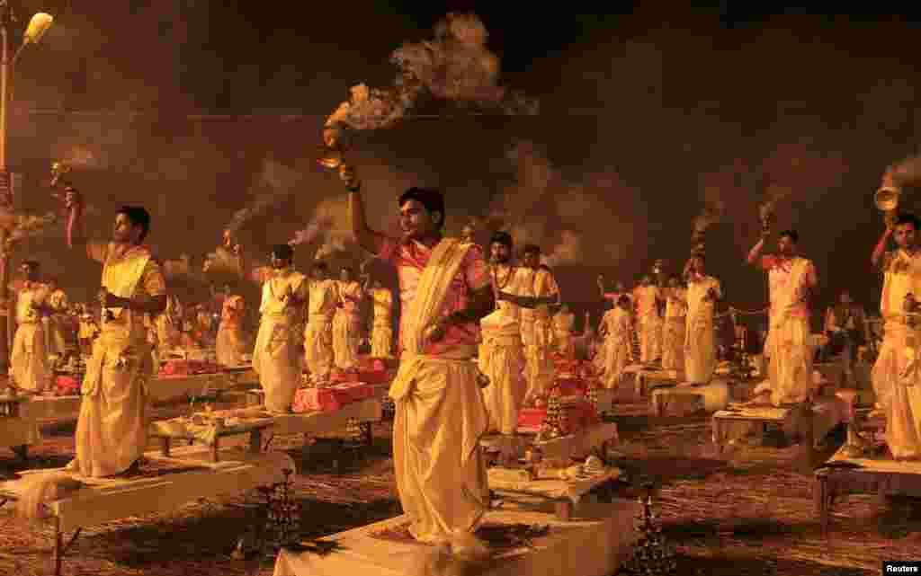Hindu priests hold traditional incense lamps as they perform a ritual known as"Aarti" on the banks of Sangam - the confluence of the Ganges, Yamuna and mythical Saraswati rivers - during the annual religious festival of Magh Mela in Allahabad, India.