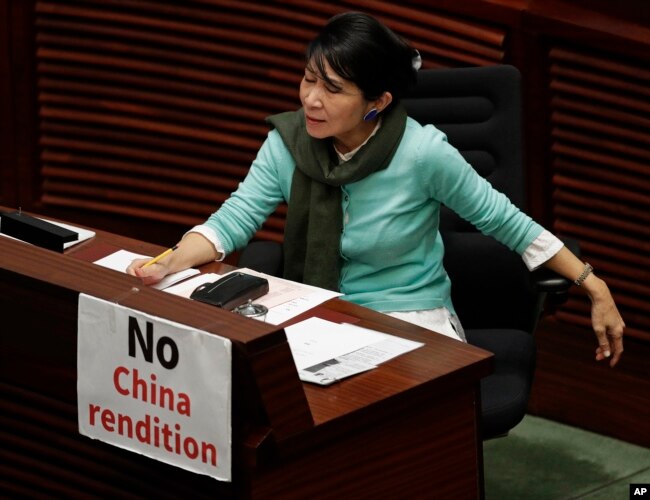 FILE - A lawmaker displays a placard to protest an extradition law at the Legislative Council, in Hong Kong, April 3, 2019.