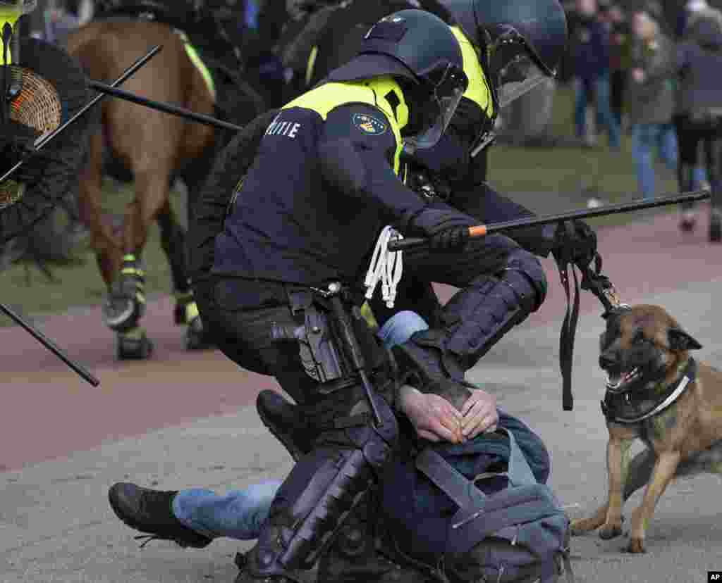 Dutch riot police kick a man during a demonstration to protest government policies including the curfew, lockdown and coronavirus related restrictions in The Hague, Netherlands.