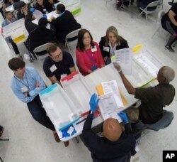 Workers at the Broward County Supervisor of Elections office, foreground, show observers ballots during a hand recount, Friday, Nov. 16, 2018, in Lauderhill, Fla.