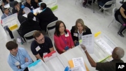 Workers at the Broward County Supervisor of Elections office, foreground, show Republican Democrat observers ballots during a hand recount, Friday, Nov. 16, 2018, in Lauderhill, Florida.