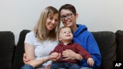 Anna Ford, left, and her partner, Sara Watson, pose with their son, Eli, in the village of Saunderstown, in Narragansett, R.I., Nov. 16, 2018.