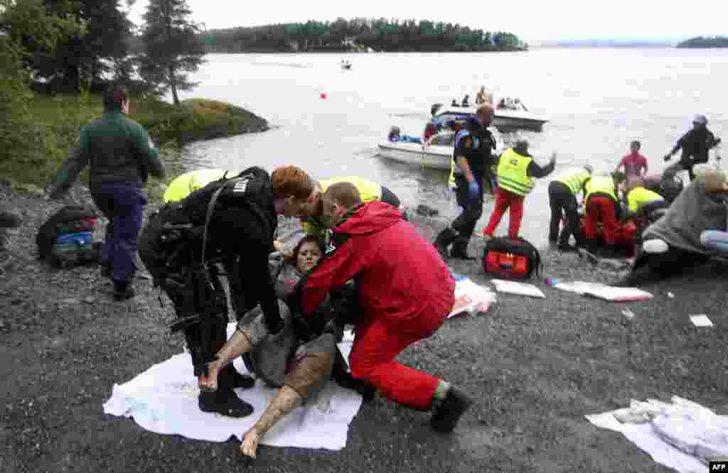 A wounded woman is brought ashore opposite Utaoya island (in the distance) after being rescued from a gunman who went on a killing rampage targeting participants in a Norwegian Labour Party youth organisation event on the island, some 40 km southwest of O