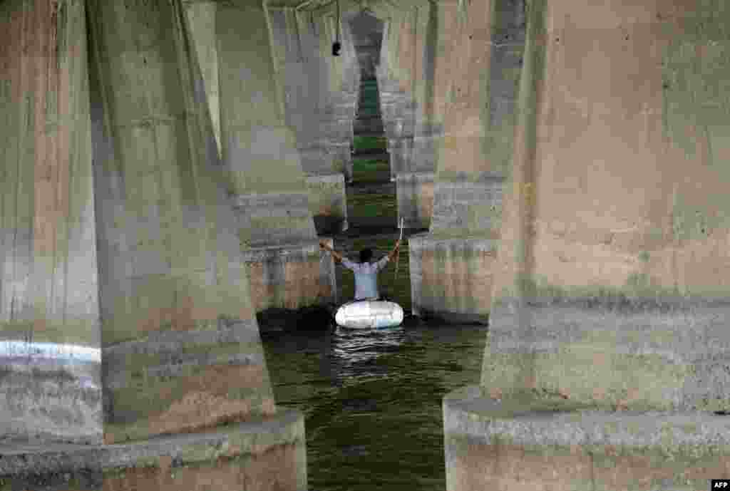 Remaja India menggunakan alat buatan sendiri untuk menyeberangi sungai Sabarmati di kota Ahmedabad.