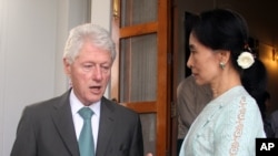 Burma opposition leader Aung San Suu Kyi, right, poses for photos with former US President Bill Clinton in front of a portrait of her late father, General Aung San, during their meeting at her lakeside residence in Rangoon, Burma, Thursday, Nov. 14, 2013.