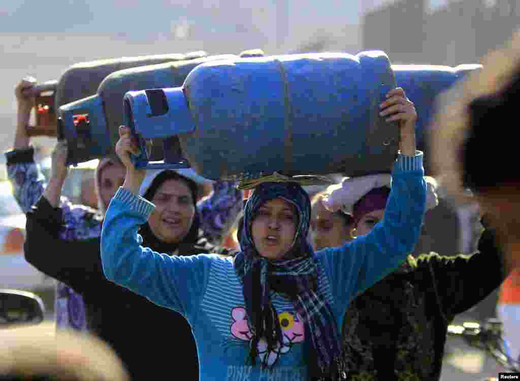 Women carry gas cylinders to fill them at a distribution point in Cairo. Egypt is going through its worst energy crisis in decades and is seeking fresh sources of natural gas.