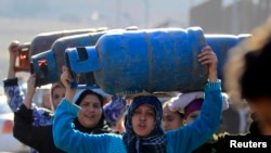 Women carry gas cylinders to fill them at a distribution point in Cairo January 19, 2015. 