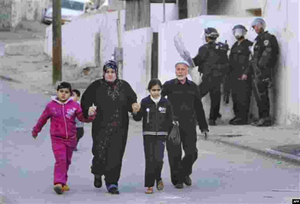 A Palestinian family walks past Israeli riot police, during a protest against Jewish settlements in the east Jerusalem neighborhood of Silwan, Monday, Dec. 27, 2010. Tensions regularly run high in Silwan, where a small group of Israeli settlers live in he
