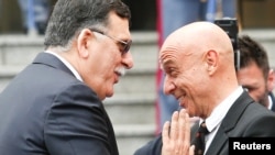 FILE - Faiez Mustafa Serraj, President of the Presidency Council of the Government of National Accord of Libya (L), is greeted by Italian Interior Minister Marco Minniti during a meeting in Rome, Italy, March 20, 2017. 