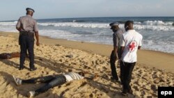Des policiers ivoiriens et le personnel médical regardent les corps des personnes tuées sur la plage en face de l'hôtel Etoile du Sud à Grand Bassam, Côte d'Ivoire, le 13 mars 2016. epa/ LEGNAN KOULA