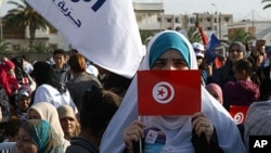 A supporter of the Islamic Ennahda party displays her national flag during a rally in Ben Arous, south of Tunis, October 21, 2011.