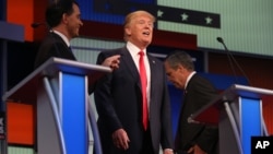 Republican presidential candidates, from left, Scott Walker, Donald Trump, and Jeb Bush are seen during a break at the first Republican presidential debate at the Quicken Loans Arena, Aug. 6, 2015, in Cleveland. 