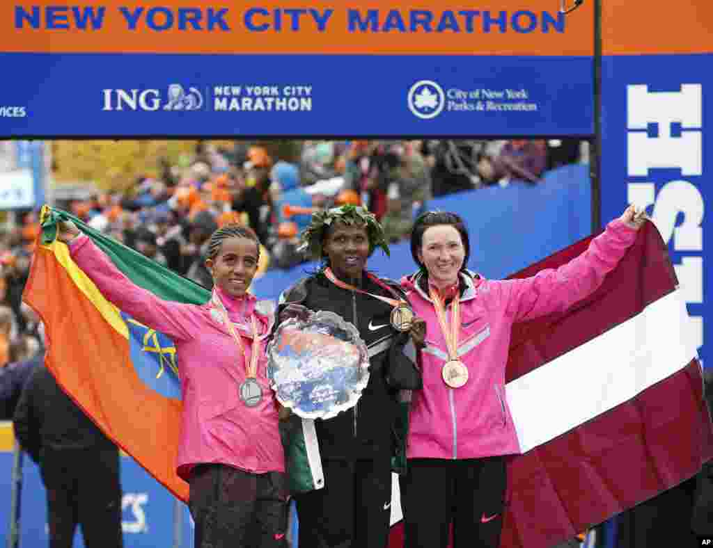 Women's winner Priscah Jeptoo of Kenya, center, second place finisher Buzunesh Deba of Ethiopia, left, and third place finisher Jelena Prokopcuka of Latvia pose with their medals after the New York City Marathon,  Nov. 3, 2013.
