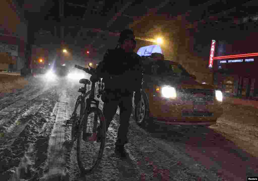 A woman walks with her bicycle during a winter storm in New York, Jan. 3, 2014. 