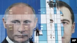 Workers attach a pre-election poster featuring Russia's President Dmitry Medvedev (r) and Prime Minister Vladimir Putin in Krasnodar, November 24, 2011