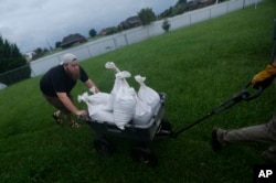 Cody McLemore pushes a wagon filled with sandbags as he fortifies his house in the flooded Clearfield Farm subdivision, in anticipation of more flooding from Tropical Storm Harvey, in Lake Charles, La., Aug. 29, 2017.