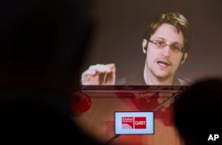 FILE - Edward Snowden, a former CIA worker before turning whistleblower, speaks via satellite at the IT fair CeBIT in Hanover, Germany, March 21, 2017.