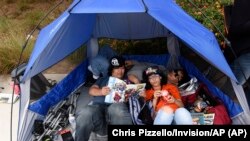 Pengunjung Comic-Con Ronald Gaffud dari San Francisco menunggu di dalam tenda untuk antre masuk ke Hall H bersama keponakannya, Kathleen, dan saudaranya, Brian di 'preview night' Comic-Con International, San Diego, 17 Juli 2019, (Foto: Chris Pizzello/Invision/AP)