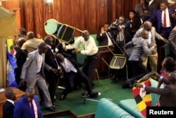 FILE - Ugandan opposition lawmakers fight with plain-clothes security personnel in the parliament while protesting a proposed age limit amendment to the constitution for the extension of the president's rule, in Kampala, Sept. 27, 2017.