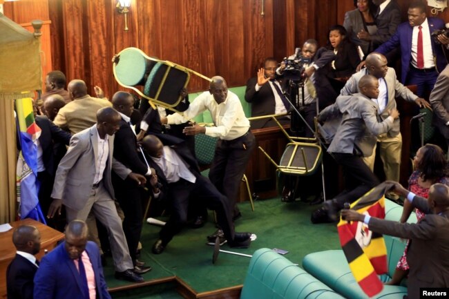 FILE - Ugandan opposition lawmakers fight with plain-clothes security personnel in the parliament while protesting a proposed age limit amendment to the constitution for the extension of the president's rule, in Kampala, Uganda, Sept. 27, 2017.