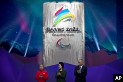 FILE - From left, 2014 Paralympic curling competitor Zhang Qiang of China, Chinese Vice Premier Liu Yandong, and Can Qi, Beijing 2022 Organizing Committee Chairman and Communist Party Secretary for Beijing, applaud as the emblem for the 2022 Beijing Winter Paralympic Games is unveiled at a ceremony at the National Aquatics Center, also known as the Water Cube, in Beijing, Dec. 15, 2017.